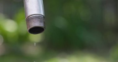 Sızdıran bir musluktan damlayan su bulanık bir arka planda. Su tasarrufu konsepti. Yüksek kalite 4k görüntü