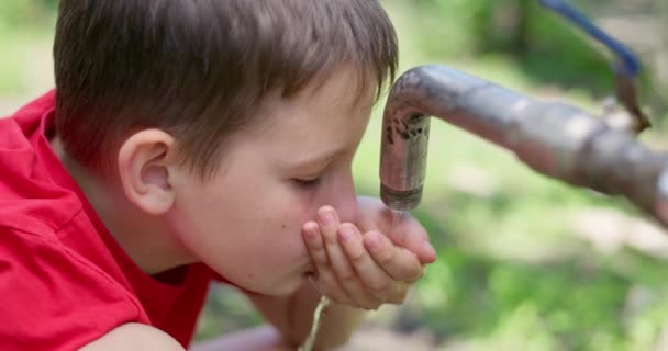 屋外の水道水から水を飲んでいる少年 高品質の4K映像 — ストック動画