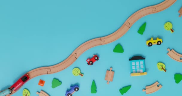 带有汽车的玩具木制火车在蓝色背景的铁路上行驶 车上有儿童玩具 复制空间 玩具商店或开发游戏中心的广告 顶部视图 高质量的4K镜头 — 图库视频影像