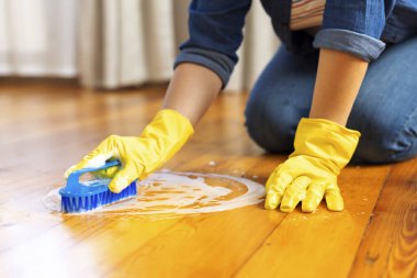 Koruyucu eldivenli genç bir kadın zemini fırça ve deterjanla yıkıyor. Temizlik servisi. Ev işleri ve ev idaresi kavramı