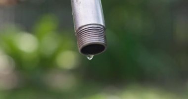 Sızdıran bir musluktan damlayan su bulanık bir arka planda. Su tasarrufu konsepti. Yüksek kalite 4k görüntü