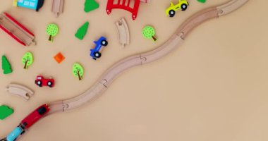 Oyuncak ahşap tren ve arabalar bej arka planda çocuk oyuncaklarıyla demiryolunda. Uzayı kopyala Oyuncakçı ya da oyun merkezi reklamı. Üst Manzara. Yüksek kalite 4k görüntü