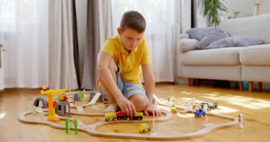 Bir çocuk çocuk demiryolu ile oynuyor. Çocuk yerdeki tahta oyuncaklarla oynuyor. Oyuncak bir tren ahşap bir demiryolunda gidiyor. Yüksek kalite 4k görüntü