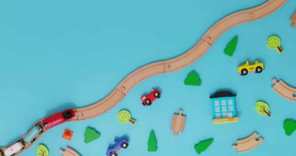 带有汽车的玩具木制火车在蓝色背景的铁路上行驶 车上有儿童玩具 复制空间 玩具商店或开发游戏中心的广告 顶部视图 高质量的4K镜头 — 图库视频影像