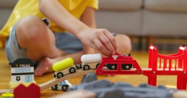 Bir çocuk çocuk demiryolu ile oynuyor. Çocuk yerdeki tahta oyuncaklarla oynuyor. Oyuncak bir tren ahşap bir demiryolunda gidiyor. Yüksek kalite 4k görüntü