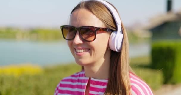Усміхнена Безтурботна Жінка Сонцезахисних Окулярах Білих Бездротових Навушниках Використовує Свій — стокове відео