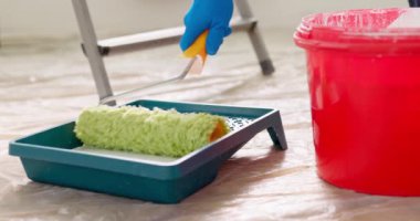 Bir adam silindiri beyaz boyaya batırıp plastik tepsiye sarar. Tamir işleri ve yaşam koşullarının iyileştirilmesi kavramı. Yüksek kalite 4k görüntü