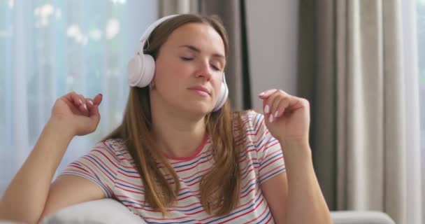 Młoda Kaukaska Kobieta Bezprzewodowych Słuchawkach Siedzi Kanapie Jasnym Pokoju Domu — Wideo stockowe