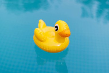 Sıcak bir yaz gününde havuzda yüzen, banyo yapan ve yüzen sarı şişme ördek. Yaz mevsimi