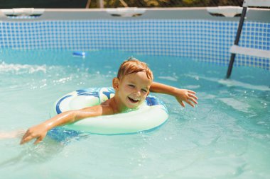 Havuzda yüzen şişme oyuncak yüzüğünde rahatlayan tatlı çocuk yaz tatilinde iyi eğlenceler. Çocuk yüzme havuzunda eğleniyor.