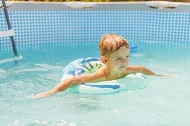 Havuzda yüzen şişme oyuncak yüzüğünde rahatlayan tatlı çocuk yaz tatilinde iyi eğlenceler. Çocuk yüzme havuzunda eğleniyor.