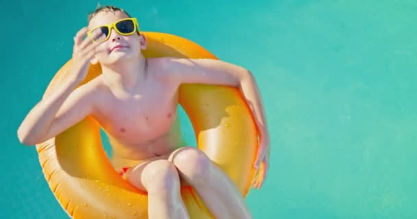 Junge Mit Gelber Sonnenbrille Schwimmt Entspannt Pool Auf Aufblasbarem Ring — Stockvideo