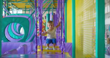 Şirin küçük çocuk, kapalı eğlence parkındaki renkli oyun parkında sürünüyor ve oynuyor. Yüksek kalite 4k görüntü