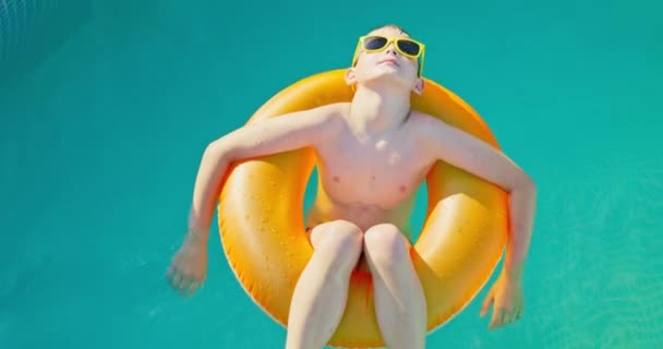 Хлопчик Жовтих Сонцезахисних Окулярах Розслабився Плаваючи Басейні Надувному Кільці Вид — стокове відео