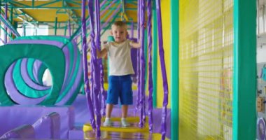 Şirin küçük çocuk, kapalı eğlence parkındaki renkli oyun parkında sürünüyor ve oynuyor. Yüksek kalite 4k görüntü