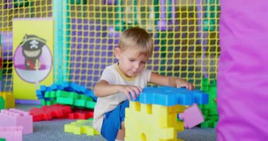 Bir çocuk, çocuk eğlence merkezinde ya da anaokulunda oyuncak yapı taşlarıyla oynar. Erken gelişim, eğlence ve eğlence kavramı. Yüksek kalite 4k görüntü