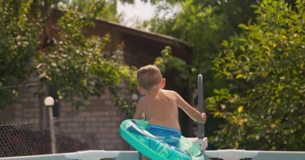 快乐的男孩带着充气环跳进游泳池 在暑假的时候喜欢在游泳池里游泳 高质量的4K镜头 — 图库视频影像