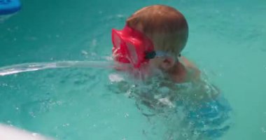 Şnorkel maskeli küçük çocuk yaz tatilinde havuza dalmayı ve yüzmeyi öğreniyor. Yüksek kalite 4k görüntü
