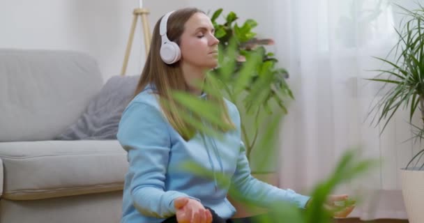 Счастливая Молодая Женщина Наушниках Практикующая Йогу Медитацию Дома Сидящая Полу — стоковое видео