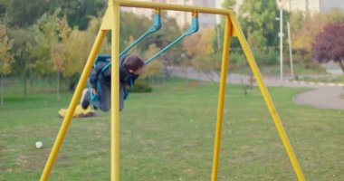 Parkta salıncakta sallanan bir çocuk, dışarıda oyun oynarken eğlenen bir çocuk. Yüksek kalite 4k görüntü