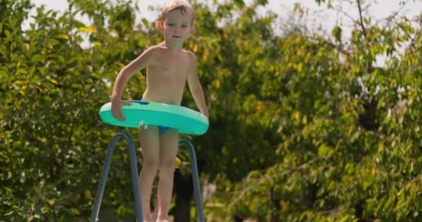 膨脹可能なリングが付いている幸せな少年はプールでジャンプし 夏休みの間にプールで泳ぐことを楽しんでいます 高品質の4K映像 — ストック動画
