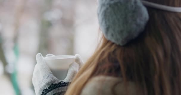 冬の女性のオーバーショルダービューは 屋外で蒸しカップを楽しんでいます — ストック動画