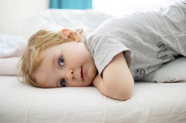 Yatakta uzanan düşünceli çocuk..