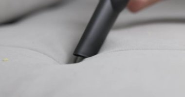 Elektrikli süpürge hortumunun gri bir kanepeden kırıntıları temizlerken ev temizliğini gösteren detaylı bir görüntüsü. Yüksek kalite 4k görüntü