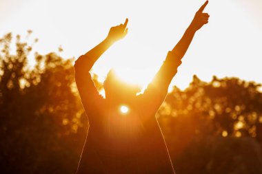 Gün batımında el kaldıran kişinin silueti. Özgürlük ve başarı kavramı. Fotokopi alanı olan arka plan fotoğrafçılığı. Motivasyon posteri için tasarım, ilham