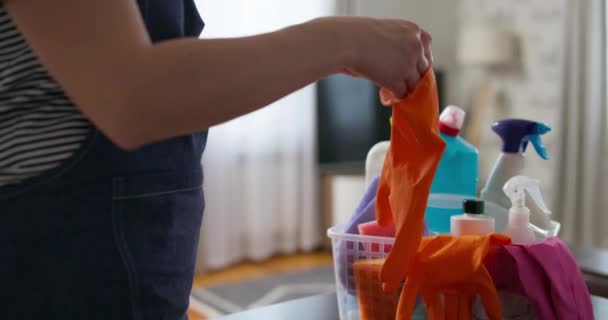 ストライプシャツやエプロンにオレンジのクリーニング手袋を置く人 バックグラウンドに物資 — ストック動画