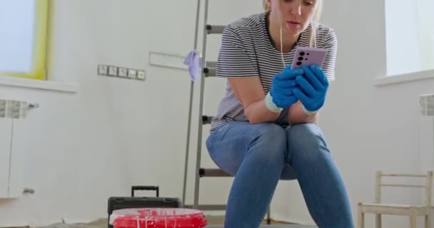Zmęczona Kobieta Siedząca Drabinie Rozmawiająca Przez Telefon Wałkiem Malowania Ręku — Wideo stockowe