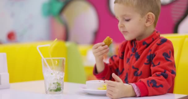 Egy Piros Pulcsis Gyerek Megkóstol Egy Csirkefalatot Színes Éttermi Háttérrel — Stock videók