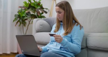 Mavi kapüşonlu kadın dizüstü bilgisayar kullanıyor ve kredi kartı tutuyor. Çevrimiçi alışveriş ve e-ticaret kavramı. Yüksek kalite 4k görüntü