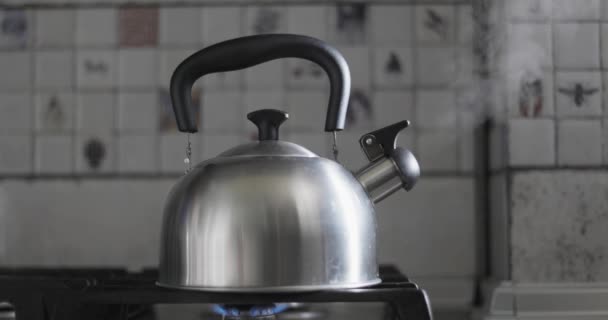 蒸汽锅炉一种带有蒸汽上升的不锈钢水壶 放在厨房里一个带有瓦片背景的点燃的煤气炉上高质量的4K镜头 — 图库视频影像