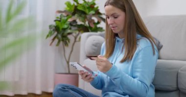 Kredi kartı ve akıllı telefon taşıyan genç bir kadın, muhtemelen online ödemeyi doğruluyor. Yüksek kalite 4k görüntü