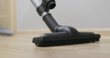 Günlük kıyafetli bir birey, modern bir elektrikli süpürgeyle parlak bir zemini süpürüyor. Yüksek kalite 4k görüntü
