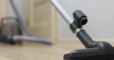 Elektrik süpürgesiyle elektrik süpürgesini çalıştırıp ev temizliğine odaklanan sıradan giysili biri. Yüksek kalite 4k görüntü