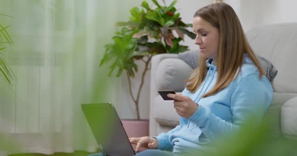 重点女性在休闲服装使用笔记本电脑和信用卡从家里网上购物 高质量的4K镜头 — 图库视频影像