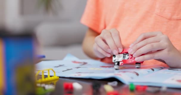 在一本说明书的基础上 用五颜六色的建筑砖把一辆红色的玩具车组装在一起的孩子们的手的特写 高质量的4K镜头 — 图库视频影像