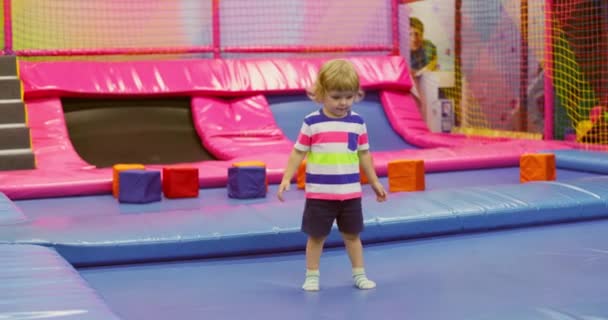 一个穿着五颜六色衣服的小孩在一个充满活力的室内游乐场里欢快地玩耍 那里有柔软的石块和踩踏物 高质量的4K镜头 — 图库视频影像