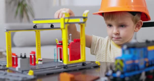 Маленький Хлопчик Капелюсі Зосередився Створенні Іграшкового Будівельного Майданчика Надихаючи Творчість — стокове відео
