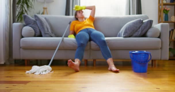 擦地板后 女人躺在沙发上休息 家庭清洁和疲劳概念 高质量的4K镜头 — 图库视频影像