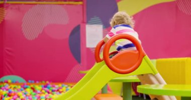 Çocuk kapalı bir oyun alanında top havuzuna kayıyor. Childs oyun zamanı ve aktivite konsepti. Yüksek kalite 4k görüntü
