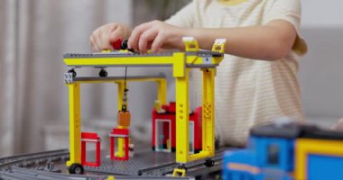 Renkli bir blok setinden model bir inşaat vincini birleştiren odaklanmış çocuk, minyatür bir çalışma alanını resmediyor. Yüksek kalite 4k görüntü