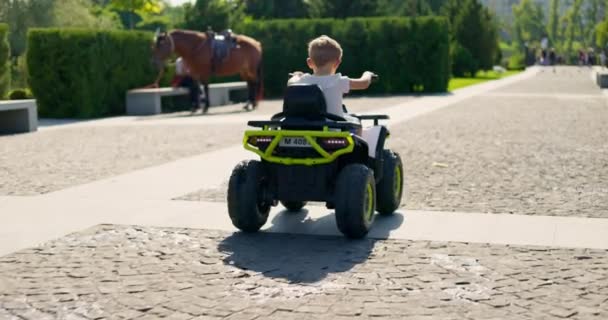 若い子供は バッテリー駆動のおもちゃオールテレイン車をコブストーンパスで運転する晴れた日を楽しんでいます 高品質の4K映像 — ストック動画