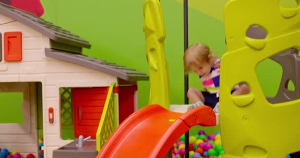 在一个充满活力的室内游戏区 一个小孩正享受着从橙色滑梯滑向球坑的乐趣 高质量的4K镜头 — 图库视频影像