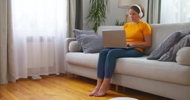 Focused Woman Casual Attire Using Laptop Home While Robot Vacuum — Stock Video