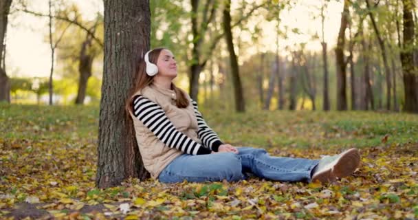 Kobieta Siedząca Pod Drzewem Jesiennym Parku Opadłymi Liśćmi Przypadkowa Scena — Wideo stockowe