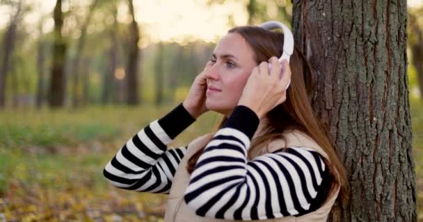 Μια Γαλήνια Νεαρή Γυναίκα Απολαμβάνει Ακούει Μουσική Λευκά Ακουστικά Ενώ — Αρχείο Βίντεο
