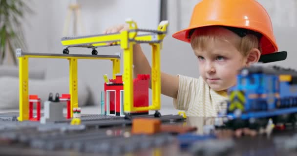 Маленький Хлопчик Капелюсі Зосередився Створенні Іграшкового Будівельного Майданчика Надихаючи Творчість — стокове відео